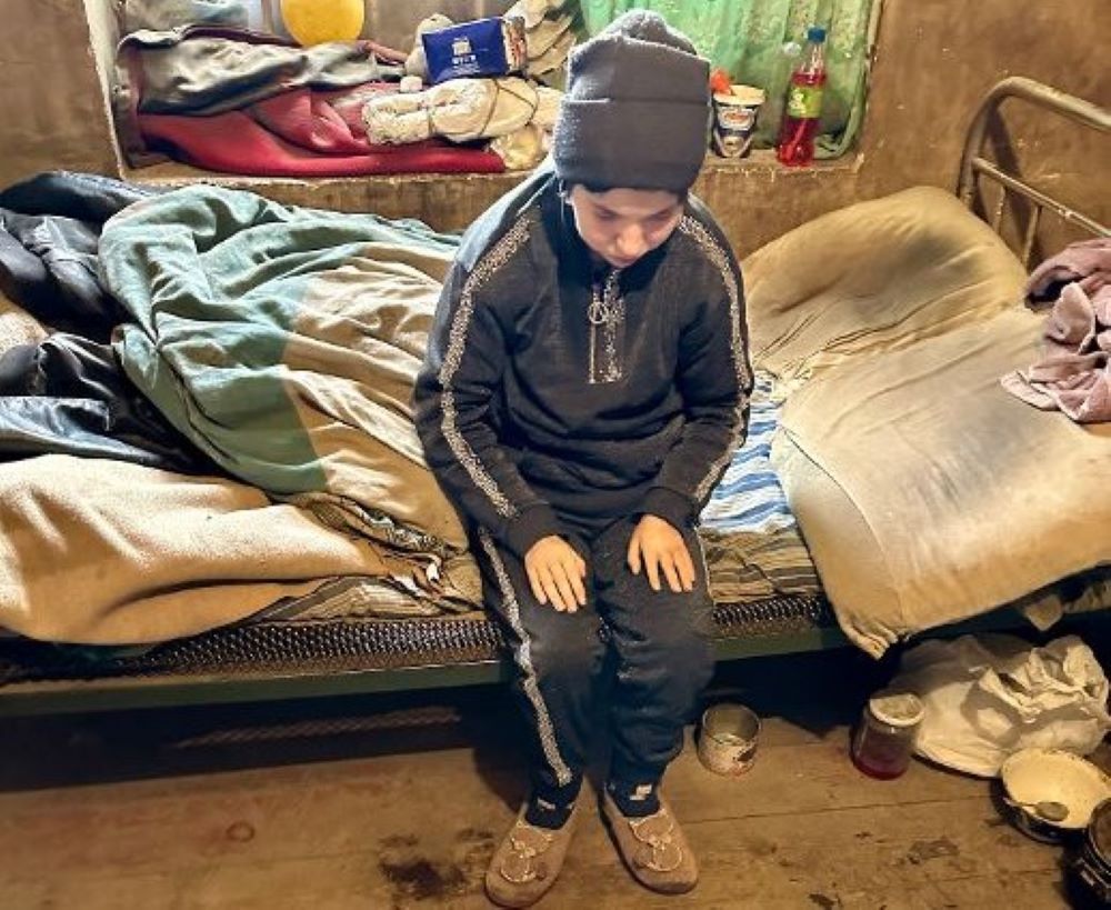 Eine blinde junge Frau sitzt auf einem schmutzigen Bett