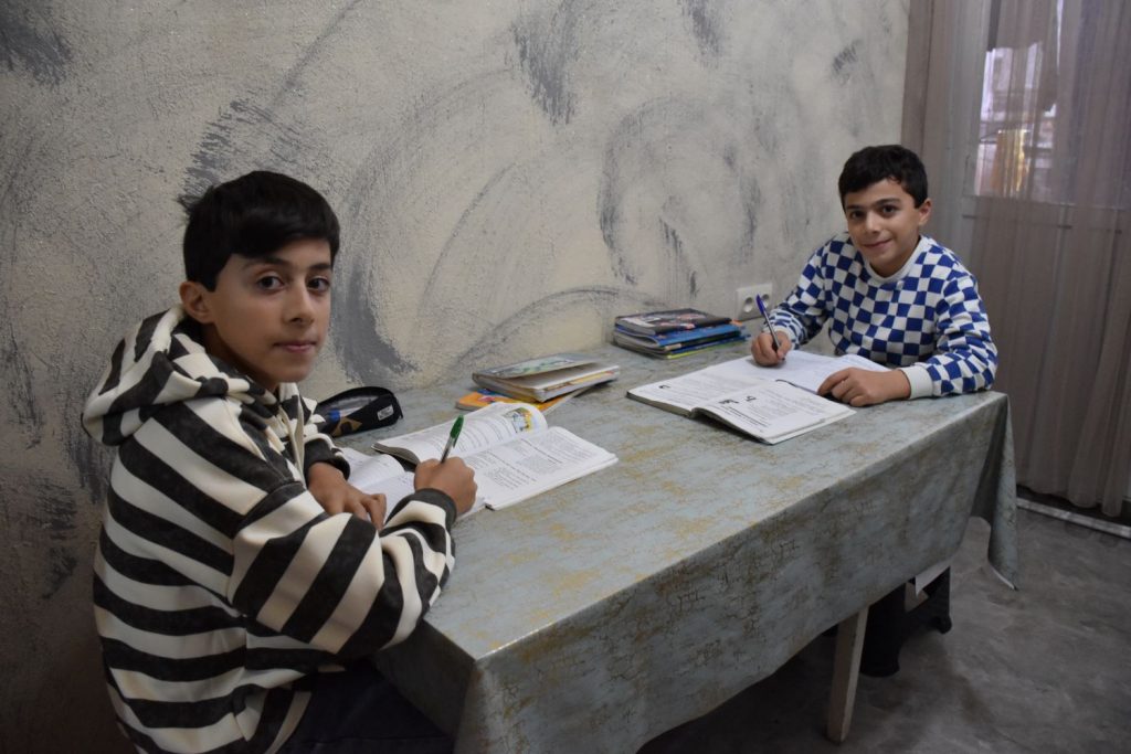 Zwei Jungen sitzen an einem Tisch und machen Hausaufgaben
