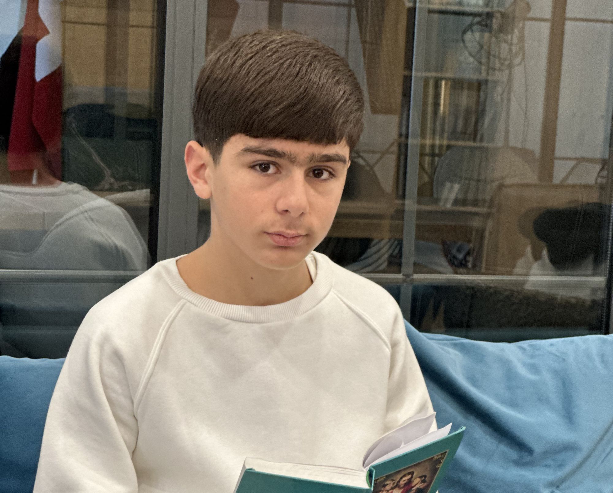 Ein Junge sitzt auf einem Sofa und hält eine Kinderbibel in der Hand.