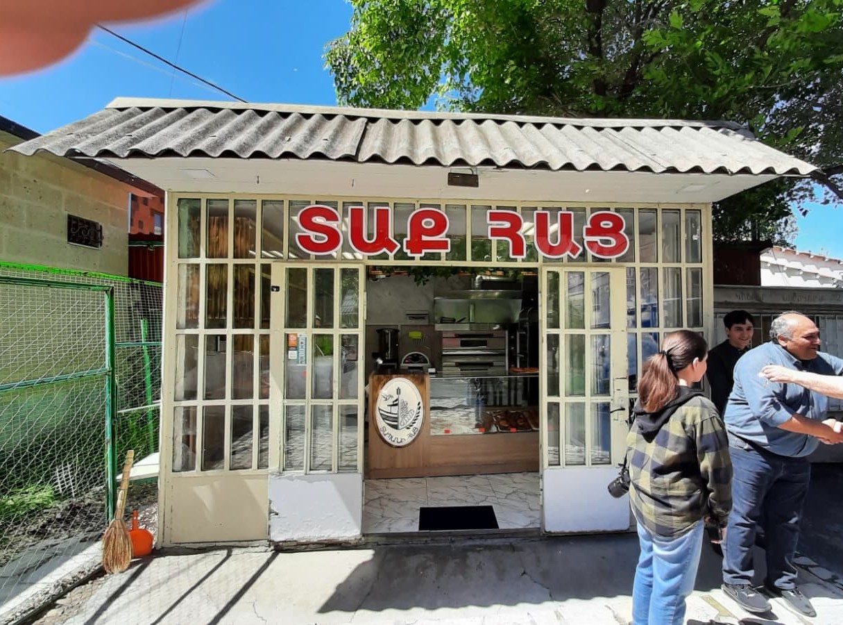 Ein kleines Gebäude mit Glasfront und Bleckdach; über der Tür die Aufschrift "Տաք Հաց" (warmes Brot)