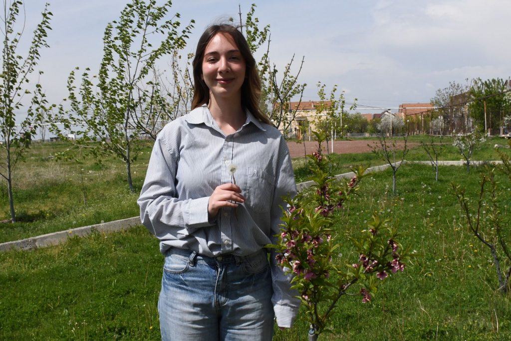 Eine junge Frau steht in einem Garten und hält eine Blume in der Hand