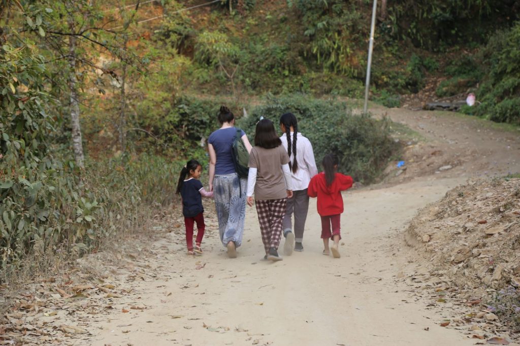 Kinder und junge Mädchen gehen auf einer unbefestigten Straße