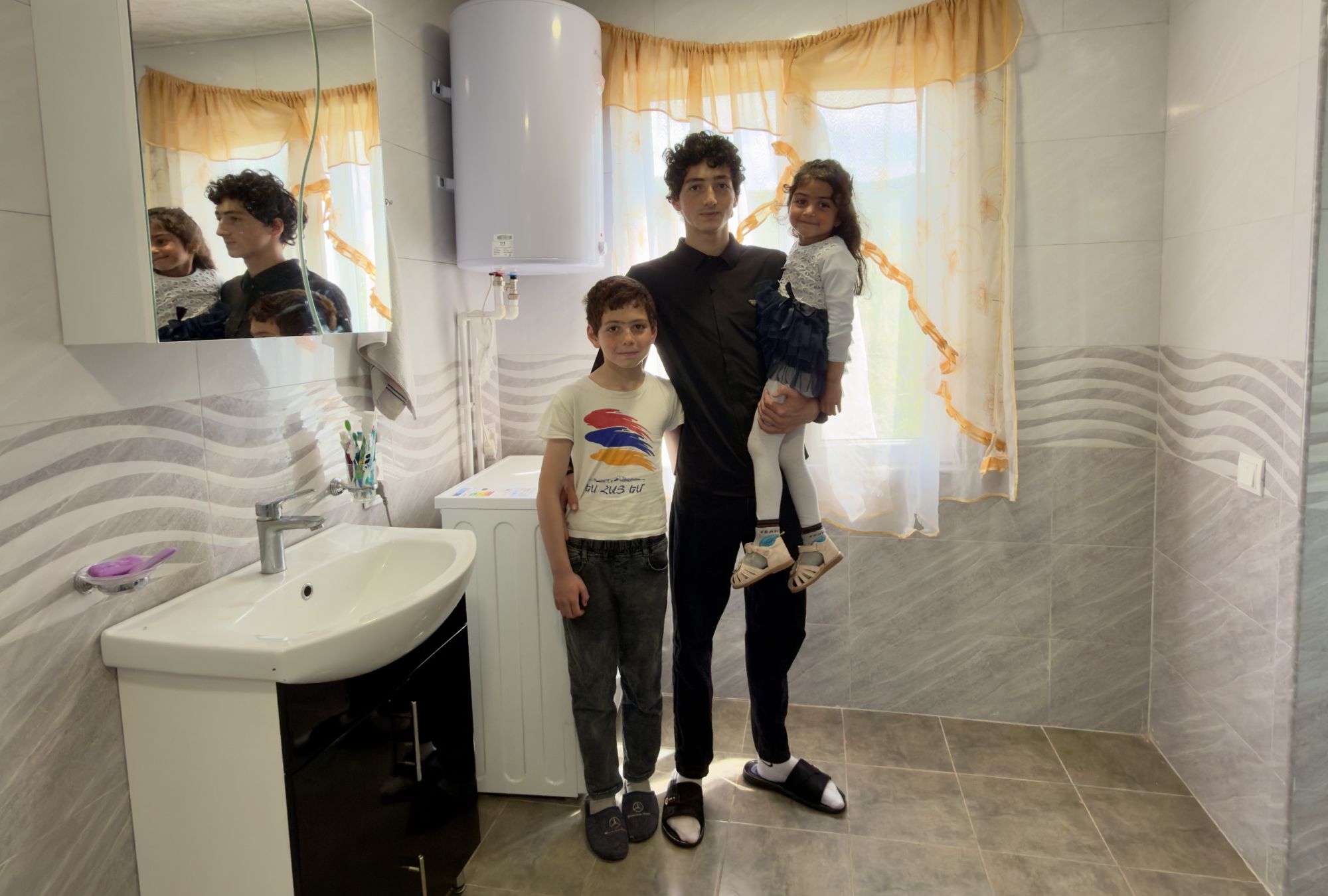 Ein Jugendlicher und zwei Kinder befinden sich in einem neuen Badezimmer