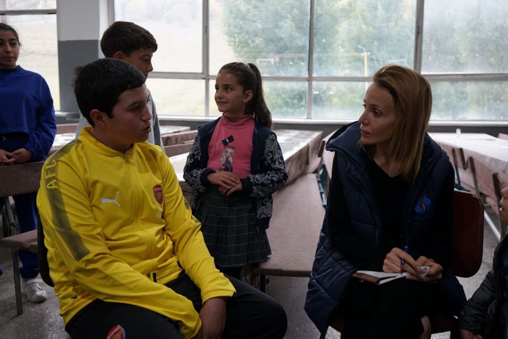 Anna Jambazian spricht mit einem älteren Jungen in einem gelben Pullover