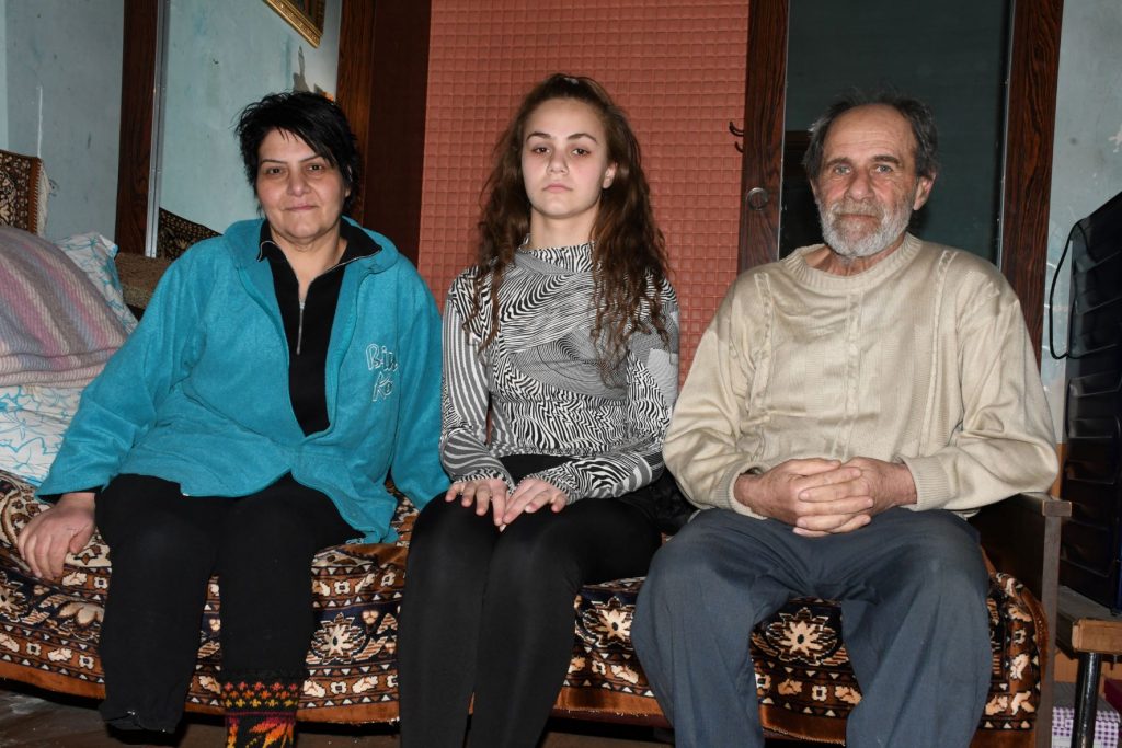 Ein Ehepaar sitzt auf einem Bett, ihre Tochter in der Mitte