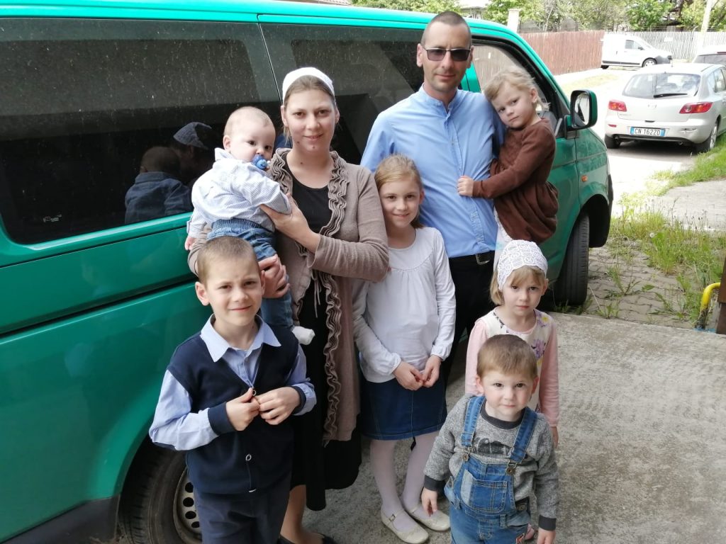 Ein Ehepaar mit sechs Kindern steht vor einem Kleinbus
