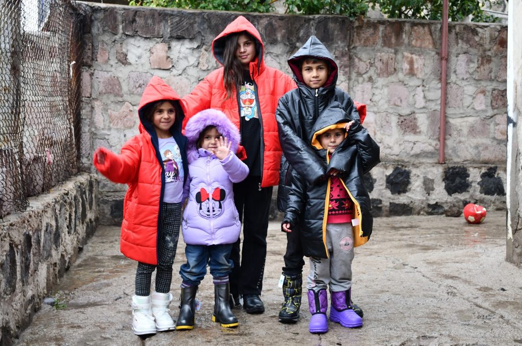 Fünf Kinder in neuer Winterkleidung lächeln in die Kamera